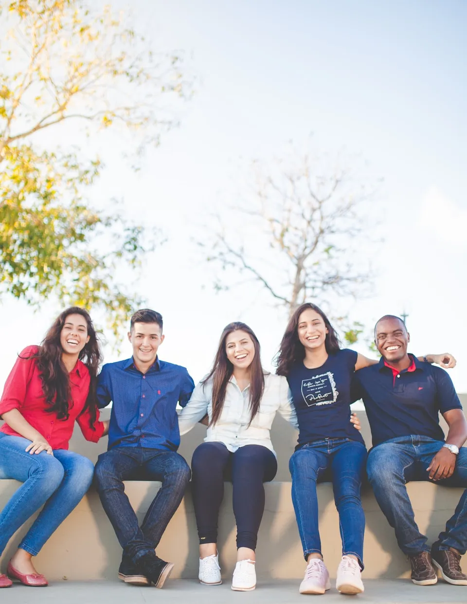 Grupo de jóvenes sentados juntos y sonriendo al aire libre